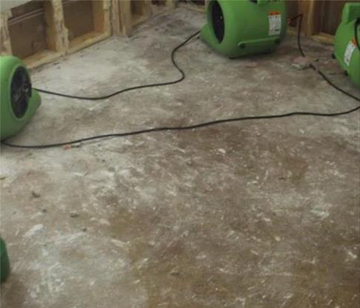 closet with concrete subfloor and green SERVPRO equipment sitting on the floor