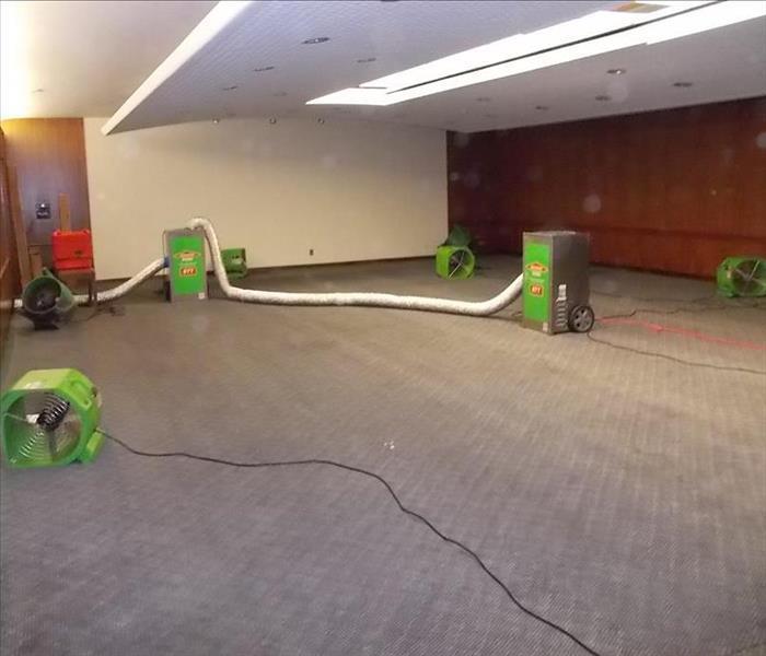 room with grey carpet and green SERVPRO equipment setup on the floor