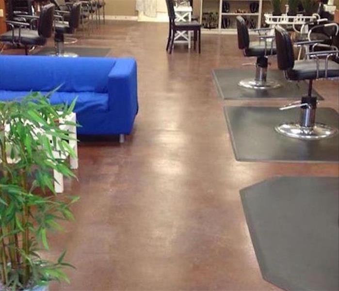 salon with brown tile floor with a blue couch and black salon chairs
