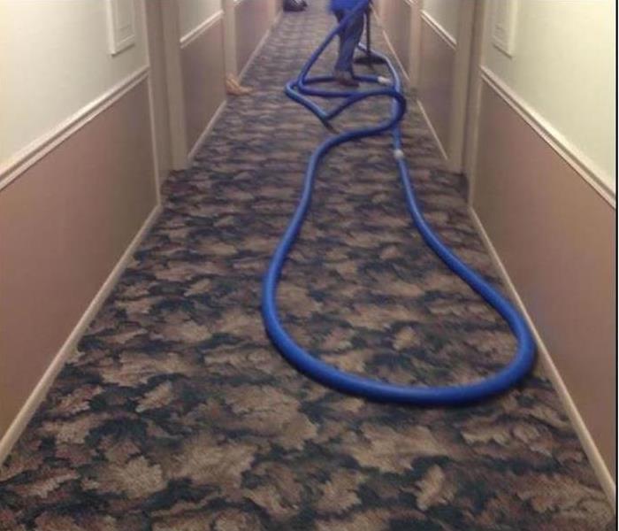 hotel hallway with employee extracting water with a vacuum