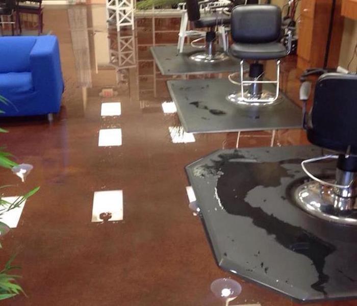 salon with water covering the brown tile floor with a blue couch and black salon chairs