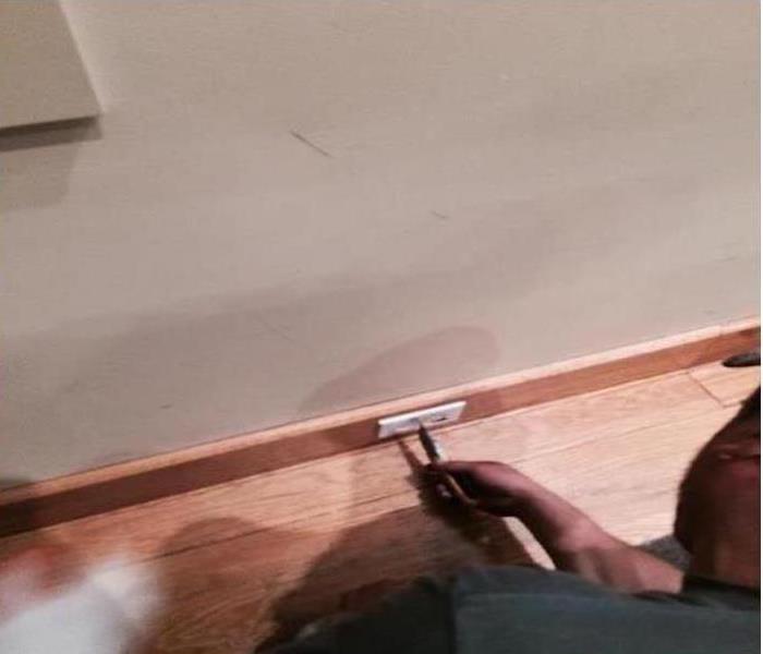 employee installing an electrical outlet on the wood baseboard
