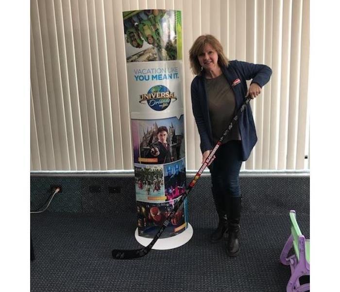 female holding a hockey stick next to a Universal Orlando sign