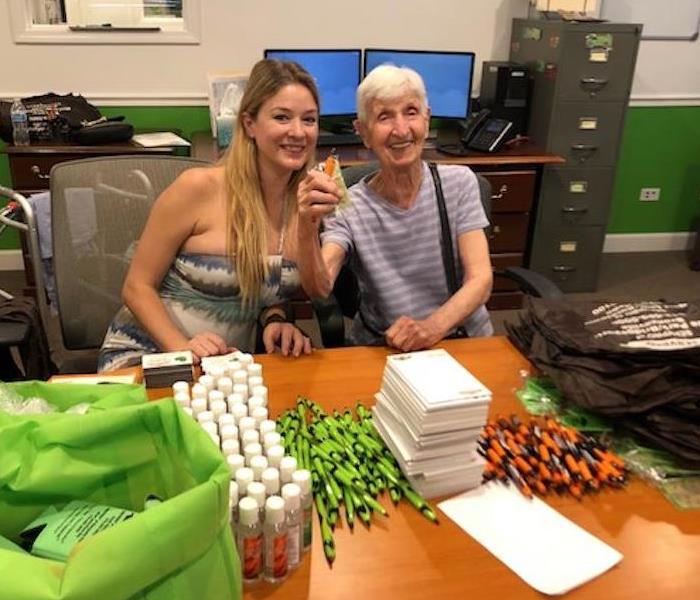 two females at a desk with SERVPRO promotional items