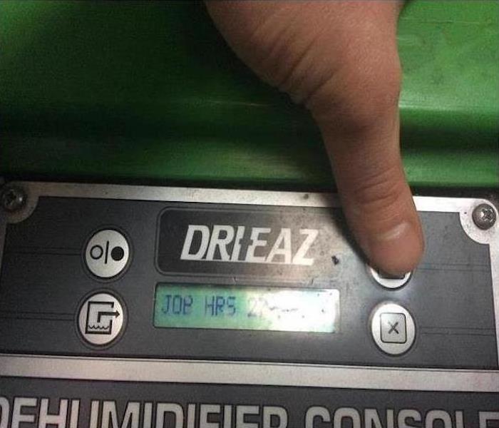 hand pushing buttons on a green dehumidifier