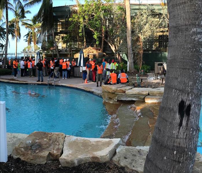 several employees standing on a pool deck in orange vests and shirts