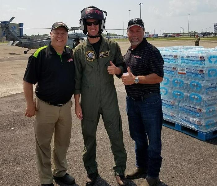two SERVPRO employees standing with a pilot giving a thumbs up