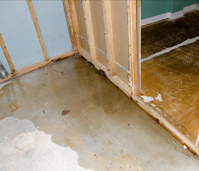 water pooling on a concrete floor next to exposed framing
