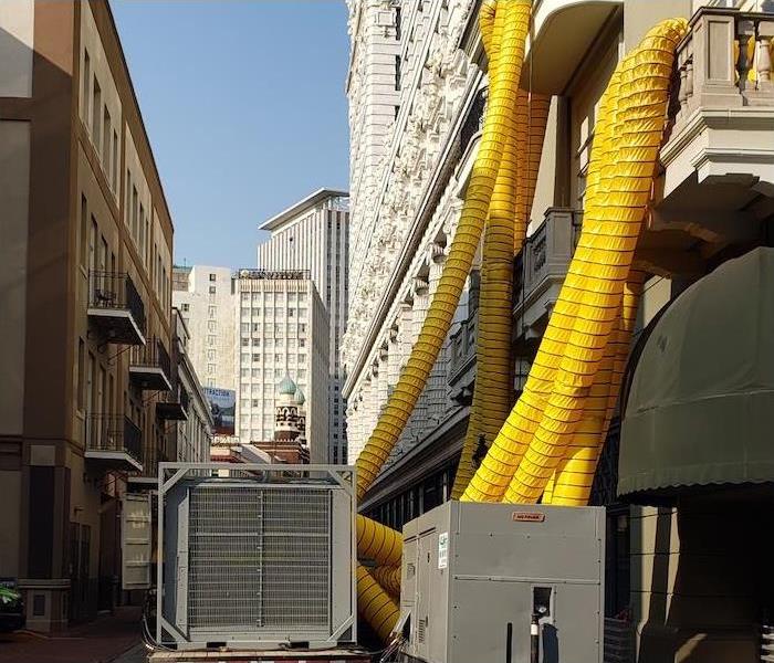 Equipment with yellow ducts going into a building with water damage
