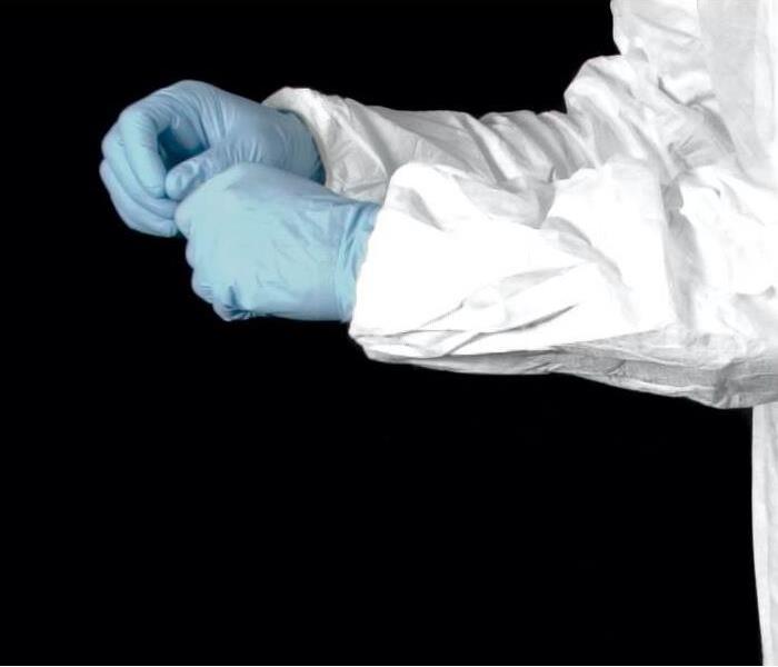 arms of a person wearing blue gloves and a white protective suit