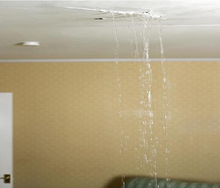 water dripping from a white ceiling with yellow wall paper on the walls
