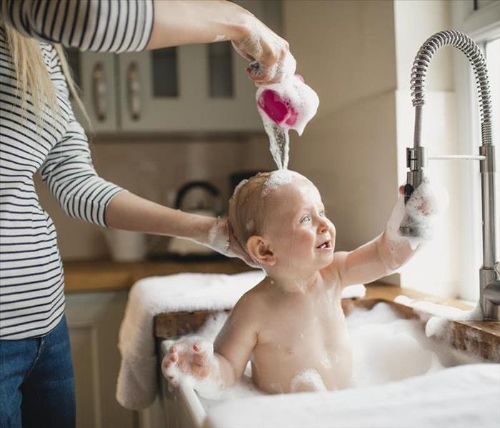 A mother giving a child a bath in a sink. 