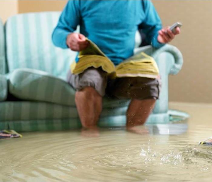 Man sitting on couch in flooded living room
